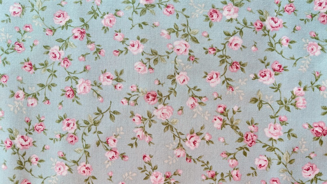 Rosen ranker på bund af støvet grøn patchworkstof.